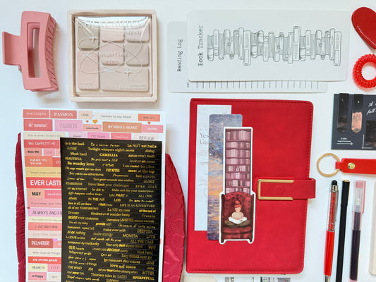 Collection of stationery items including a red notebook, pink eraser, and various office supplies on a white background.