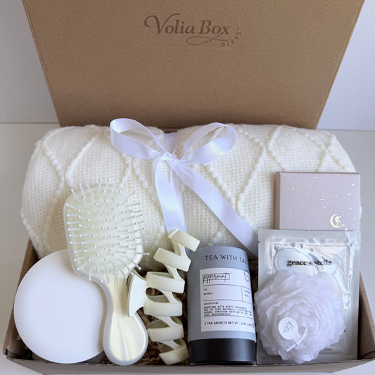 Self care gift set flat lay with mirror, eye patches, candle, tea and chocolate